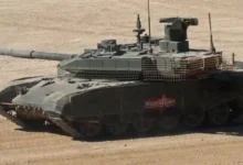 دبابة القتال الرئيسية T-90M مع درع شبكي على الجزء السفلي من برجها ودرع شرائحي في مؤخرة البرج ومركبة الدبابة.