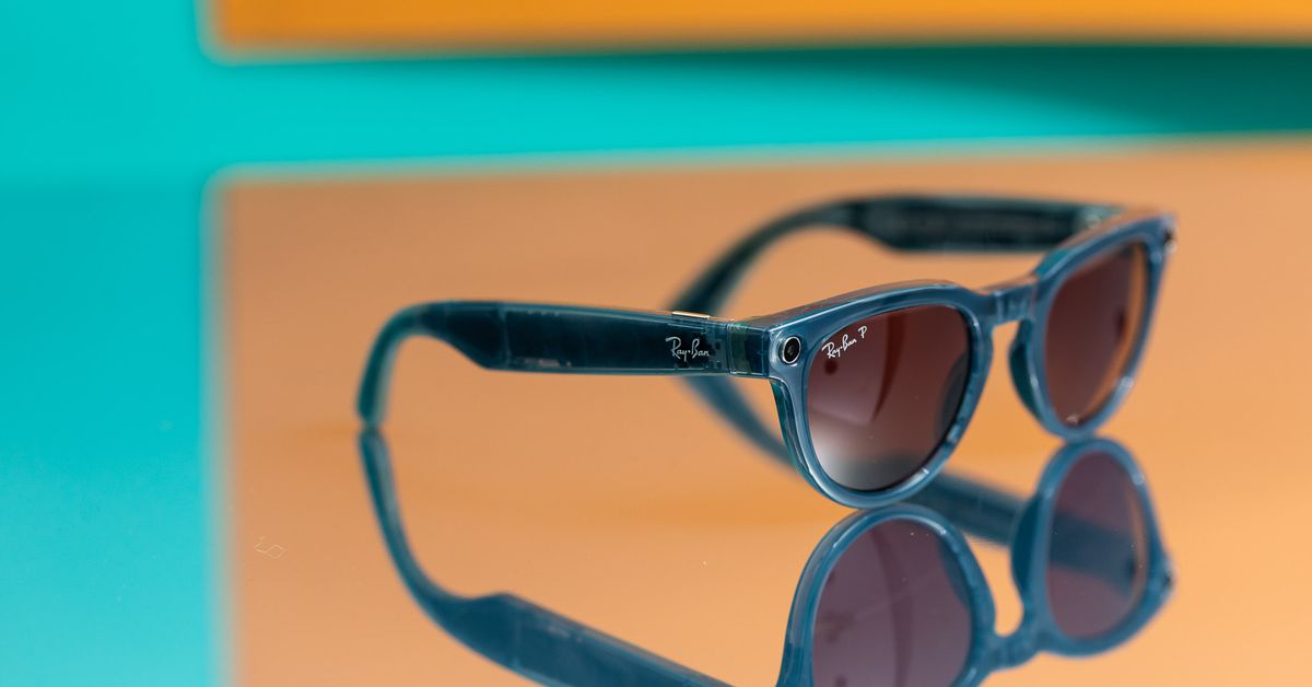 Blue Ray-Ban Meta Smart Glasses with pinkl enses on a colorful mirror.