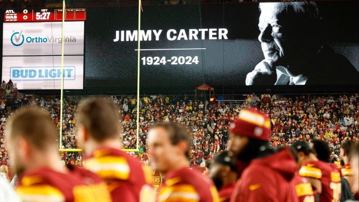 American football fans observe a moment’s silence to mark the passing of former president Jimmy Carter