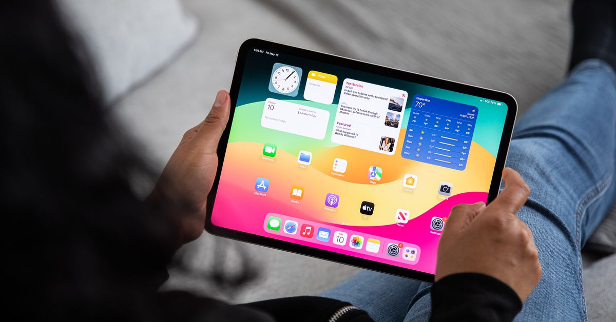 Image over the shoulder of a seated person holding an iPad Pro.