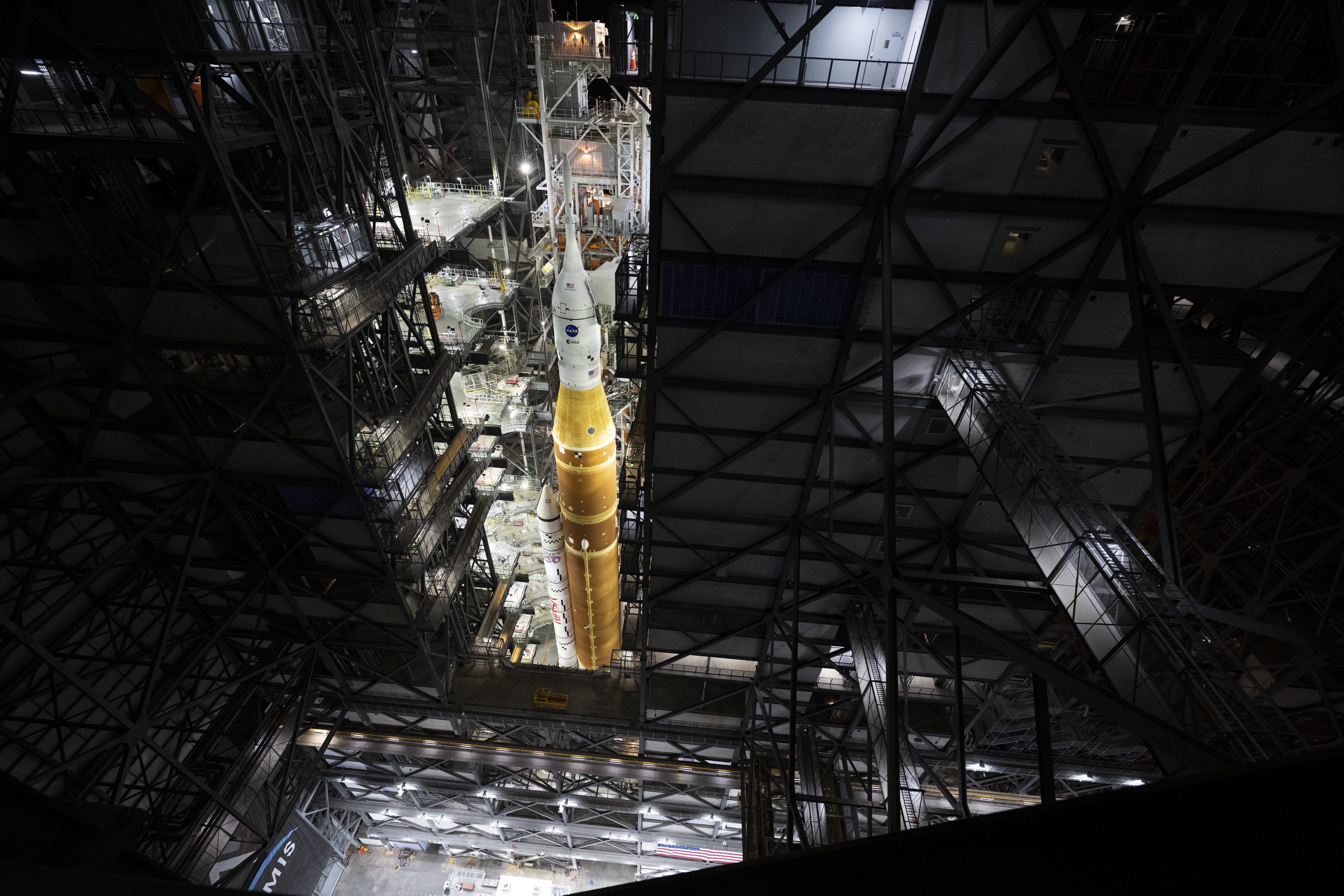 A giant orange and white rocket standing inside a towering rocket