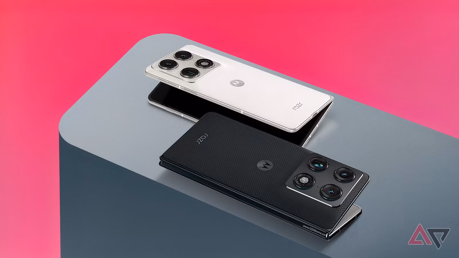 Two Motorola Razr Fold Smartphones One In Lily White And One In Blackened Blue Resting On A Grey Sur Avif