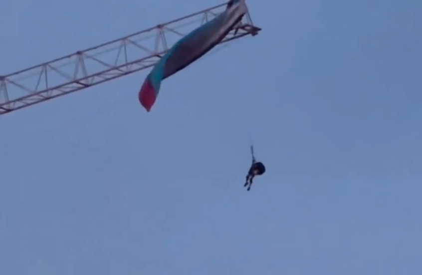 شاهد.. طيار شراعي علق بمظلته فوق رافعة بناء في الصين