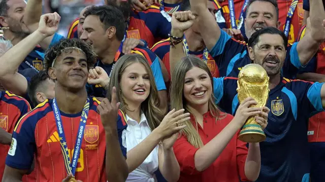 الأميرة صوفيا ترفع كأس العالم وسط احتفالات المنتخب الإسباني بالتتويج بلقب مونديال 2026، وإلى جانبها الأميرة ليونور والمهاجم لامين يامال، عقب الفوز على الأرجنتين في المباراة النهائية على ملعب نيويورك/نيوجيرسي في إيست راذرفورد بالولايات المتحدة، في 19 يوليو/تموز 2026.