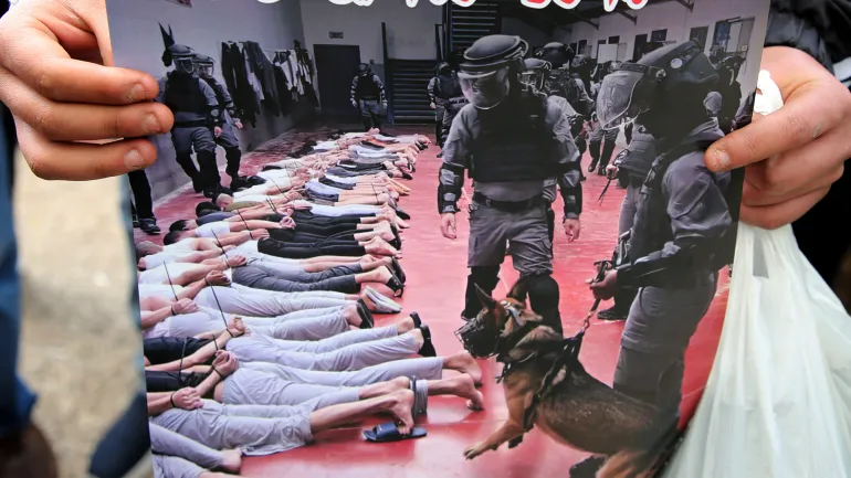 نابلس، فلسطين – 2026/04/14: فلسطيني يحمل لافتة تصور تعذيب ذويه وصورة لكلب يهاجم معتقلين في السجون الإسرائيلية خلال المظاهرة التي شهدتها مدينة نابلس بالضفة الغربية. تجمع أهالي أبنائهم المعتقلين في سجون الاحتلال الإسرائيلي للمطالبة بالإفراج عنهم. (تصوير ناصر اشتية/SOPA Images/LightRocket عبر Getty Images)
