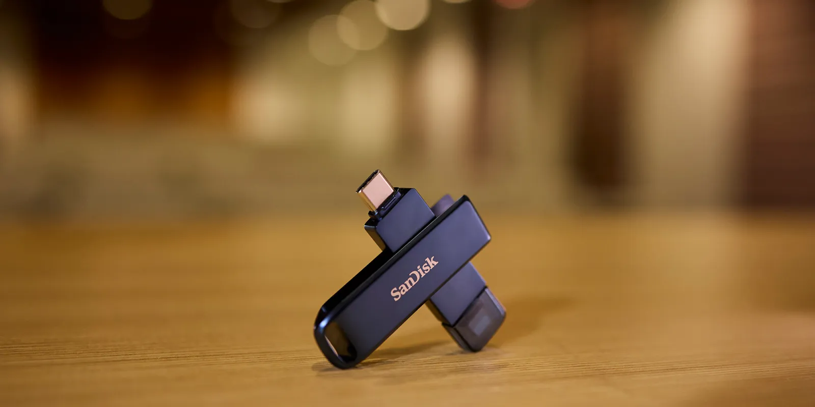 SANDISK Phone Drive لجهاز iPhone معروض على مكتب وخلفه إضاءة خارج نطاق التركيز