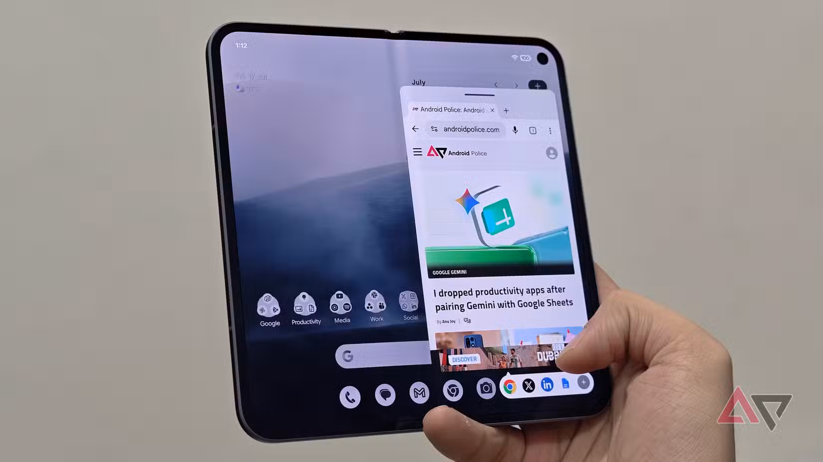 A person holding an unfolded Google Pixel Fold showing a web browser floating window open on the right side of the main display screen