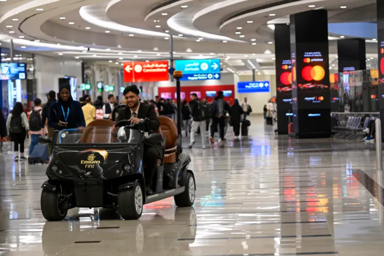 دبي، الإمارات العربية المتحدة – 19 فبراير: أحد موظفي طيران الإمارات يقود عربة كهربائية للركاب في مطار دبي الدولي في 19 فبراير 2025، في دبي، الإمارات العربية المتحدة. وفقًا لشركة مطارات دبي، وهي هيئة المطار التي تمتلك وتدير المطارات في دبي، فإن مطار دبي الدولي هو المطار الدولي الرئيسي الذي يخدم دبي، الإمارات العربية المتحدة، وهو أكثر المطارات ازدحامًا في العالم من حيث حركة الركاب الدولية اعتبارًا من عام 2023. وهو أيضًا أكثر المطارات ازدحامًا في الشرق الأوسط اعتبارًا من عام 2023، وثاني أكثر المطارات ازدحامًا في العالم من حيث حركة الركاب اعتبارًا من عام 2023، وأكثر المطارات ازدحامًا بحركات إيرباص A380 وبوينغ 777، و المطار الذي يضم أعلى متوسط لعدد الركاب لكل رحلة. وفي عام 2023، تعامل المطار مع 87 مليون مسافر و1.81 مليون طن من البضائع وسجل 416,405 حركة للطائرات. (تصوير هوراسيو فيلالوبوس#كوربيس/كوربيس عبر غيتي إيماجز)